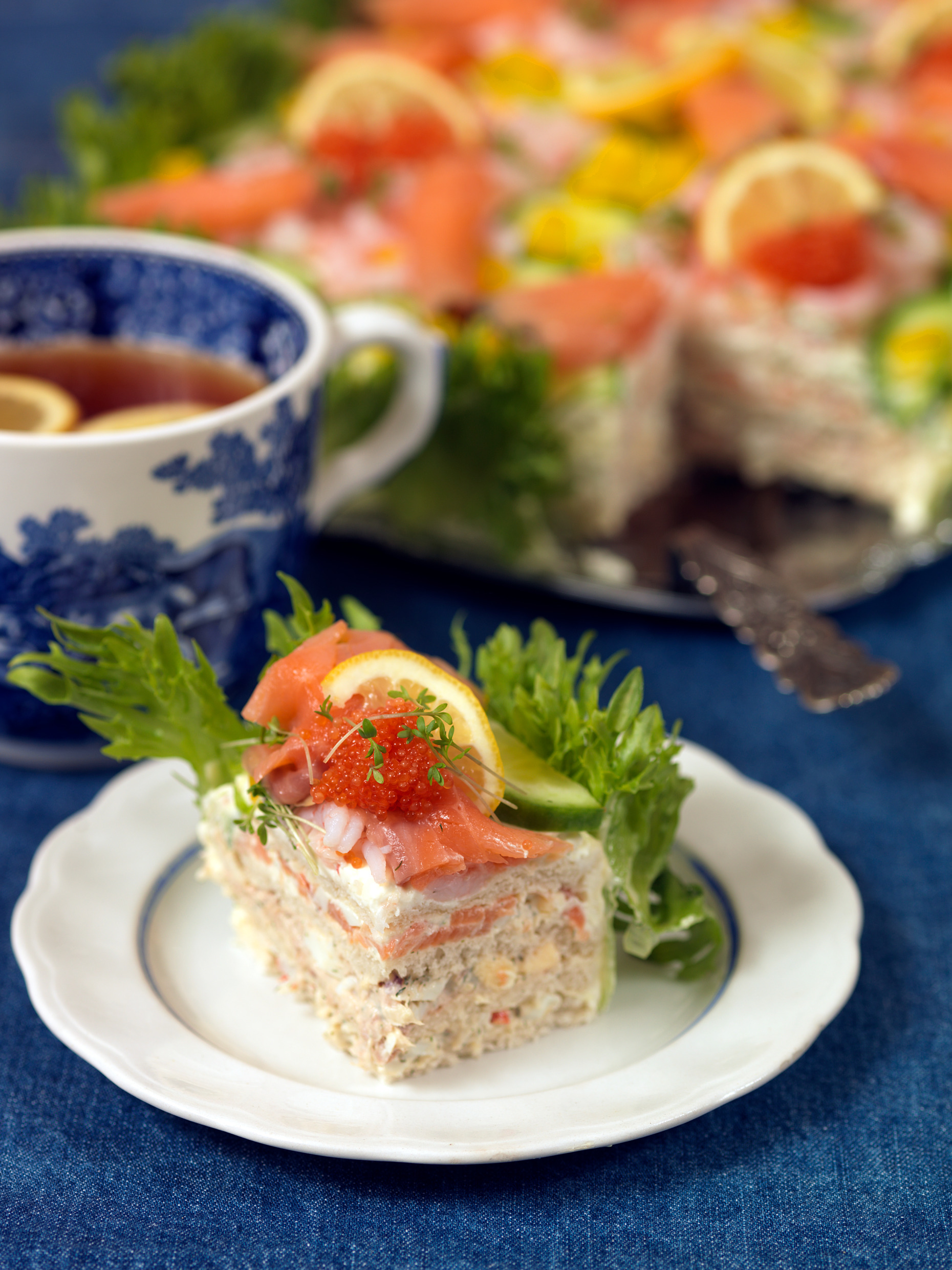 Smörgåstårta, schwedische Sandwich-Torte mit Lachs und Garnelen, auf einem Teller serviert.