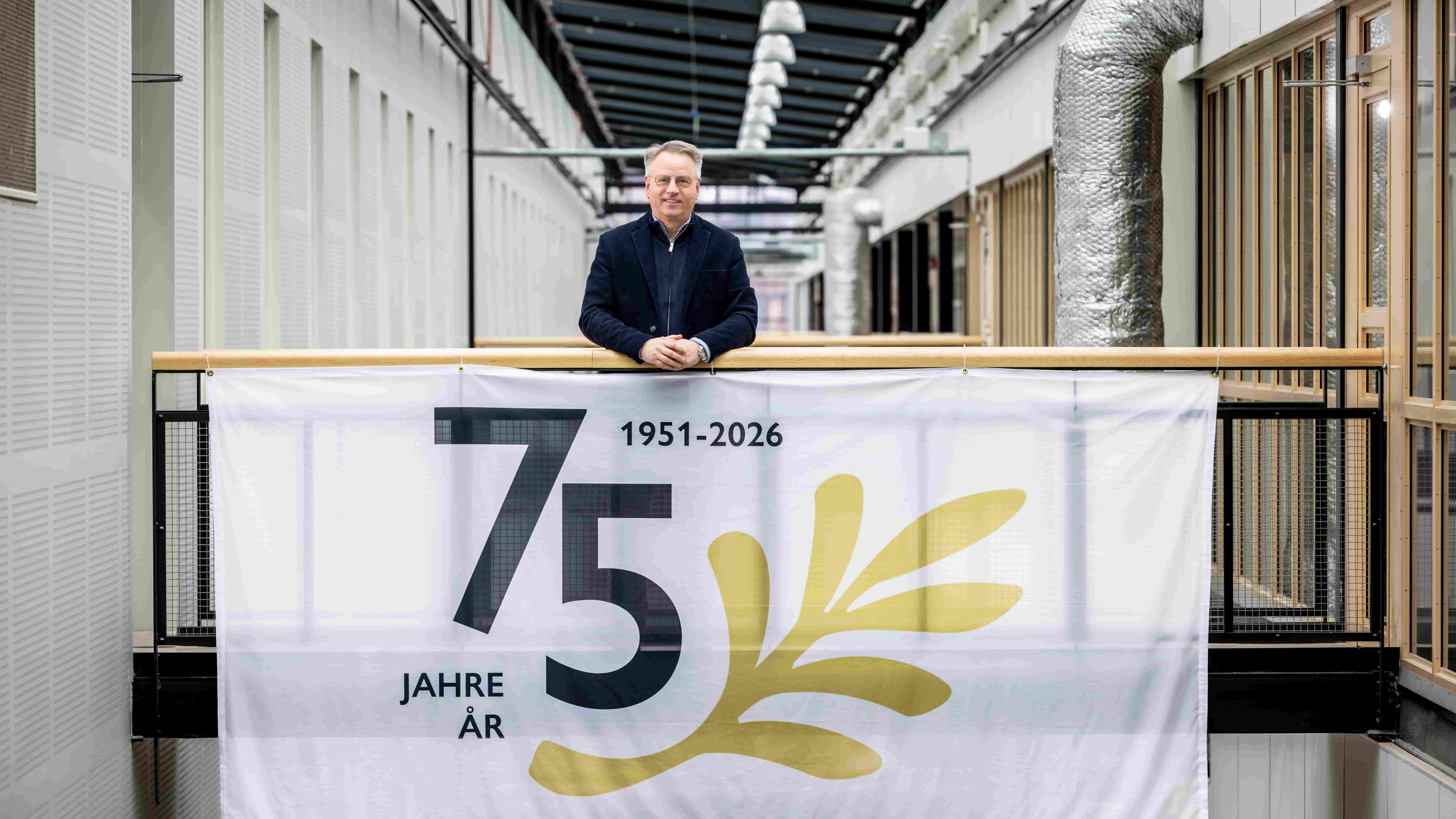 Ralph‑Georg Tischer steht hinter einem Banner zum 75‑jährigen Jubiläum der Deutsch‑Schwedischen Handelskammer.