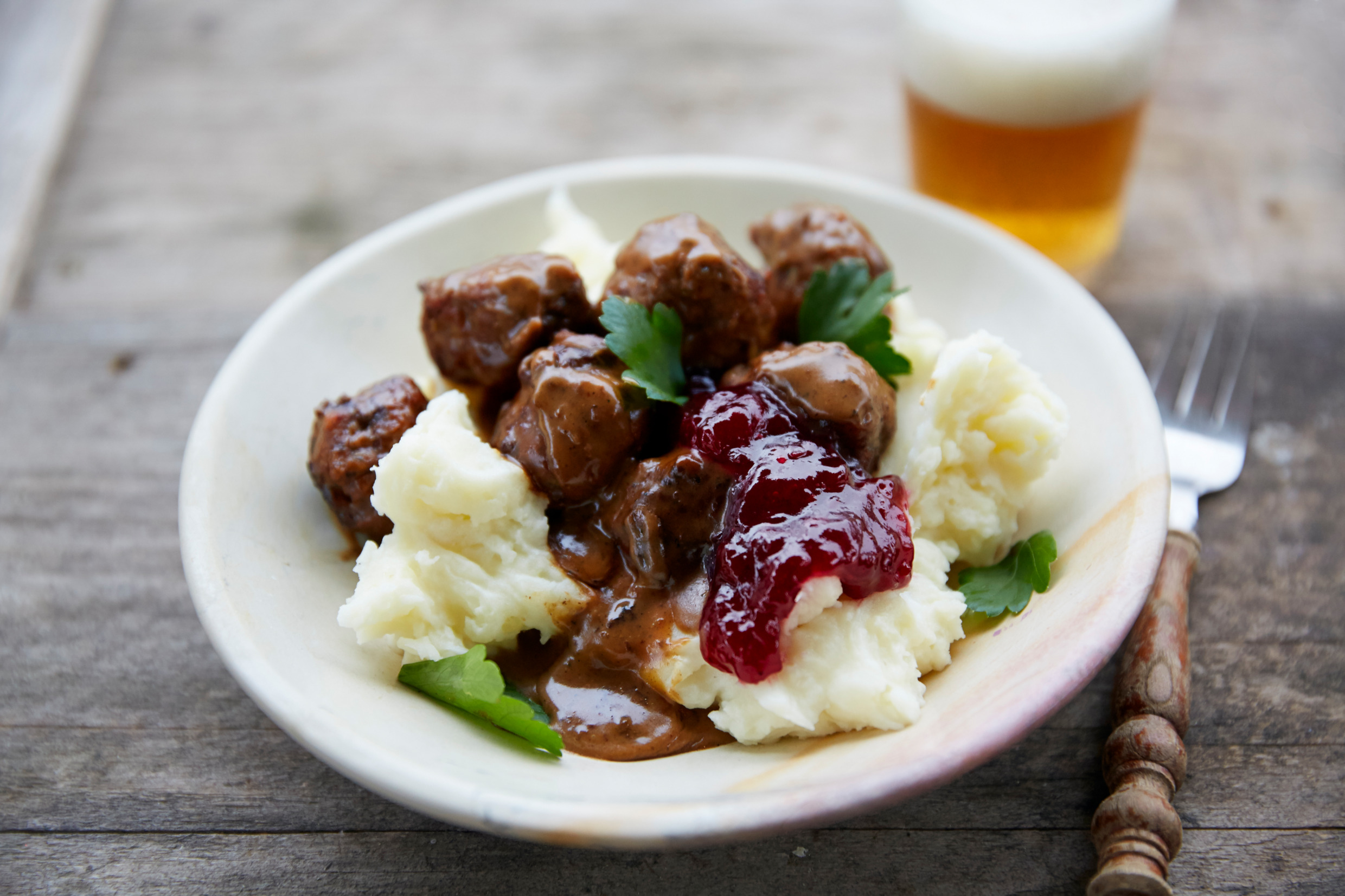Köttbullar, schwedische Fleischbällchen, serviert mit Kartoffelpüree, Rahmsauce und Preiselbeeren.