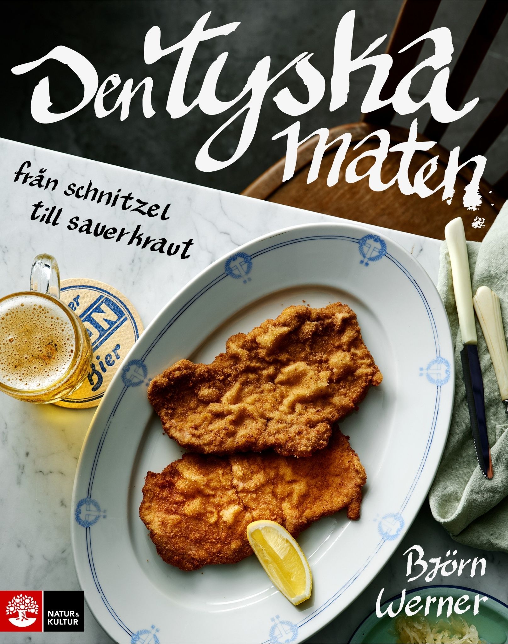  Ett bokomslag med titeln ”Den tyska maten” i stor ljus text längst upp och undertiteln ”från schnitzel till sauerkraut” i mindre stil. I mitten ligger två panerade och stekta schnitzlar på en vit tallrik med en citronskiva. Bredvid står ett glas öl och bestick på en ljus bordsyta. Författarnamnet ”Björn Werner” står längst ned till höger. Ge feedback om BizChat
