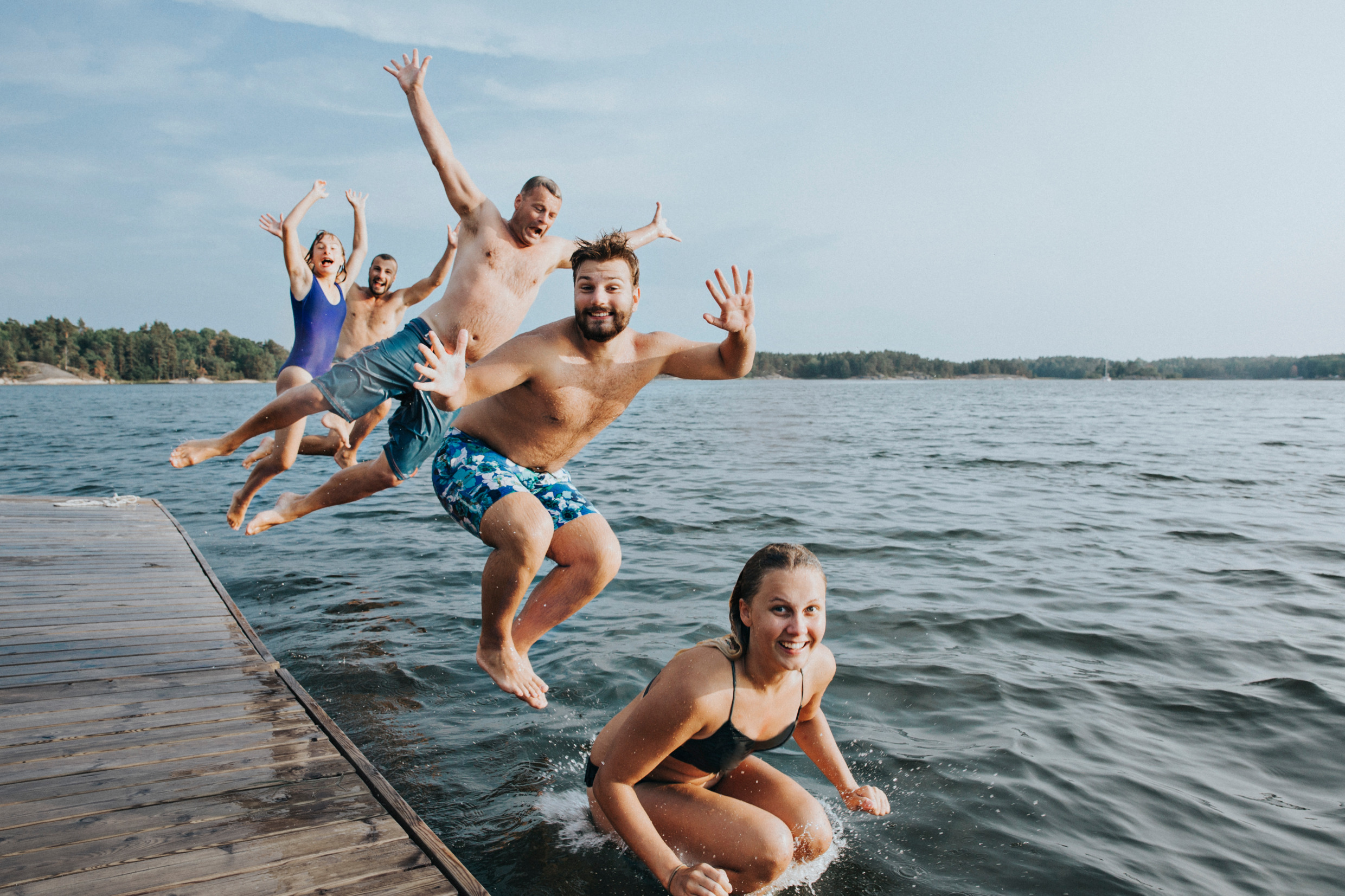 Eine Gruppe badender Personen in Schweden, die ins Wasser springen.