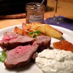 En tallrik med lammstek, klyftpotatis, sås och örtgelé