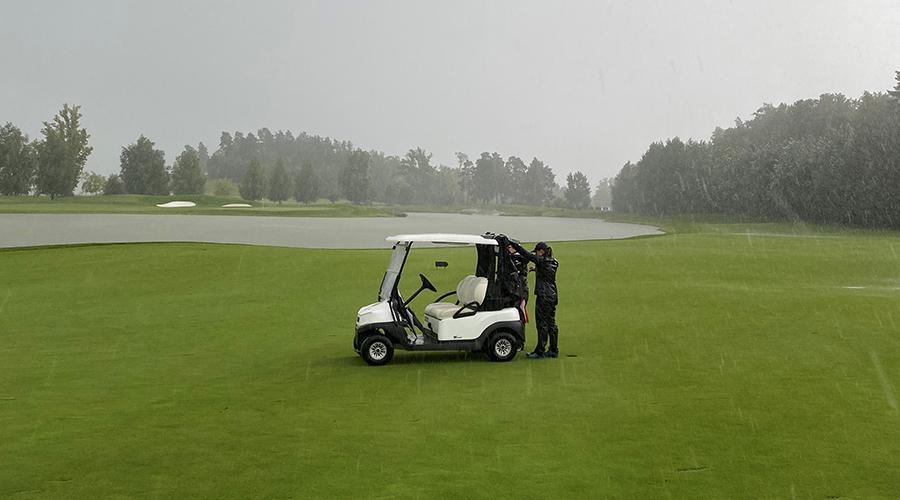 Två damer i ösregn på golfbanan