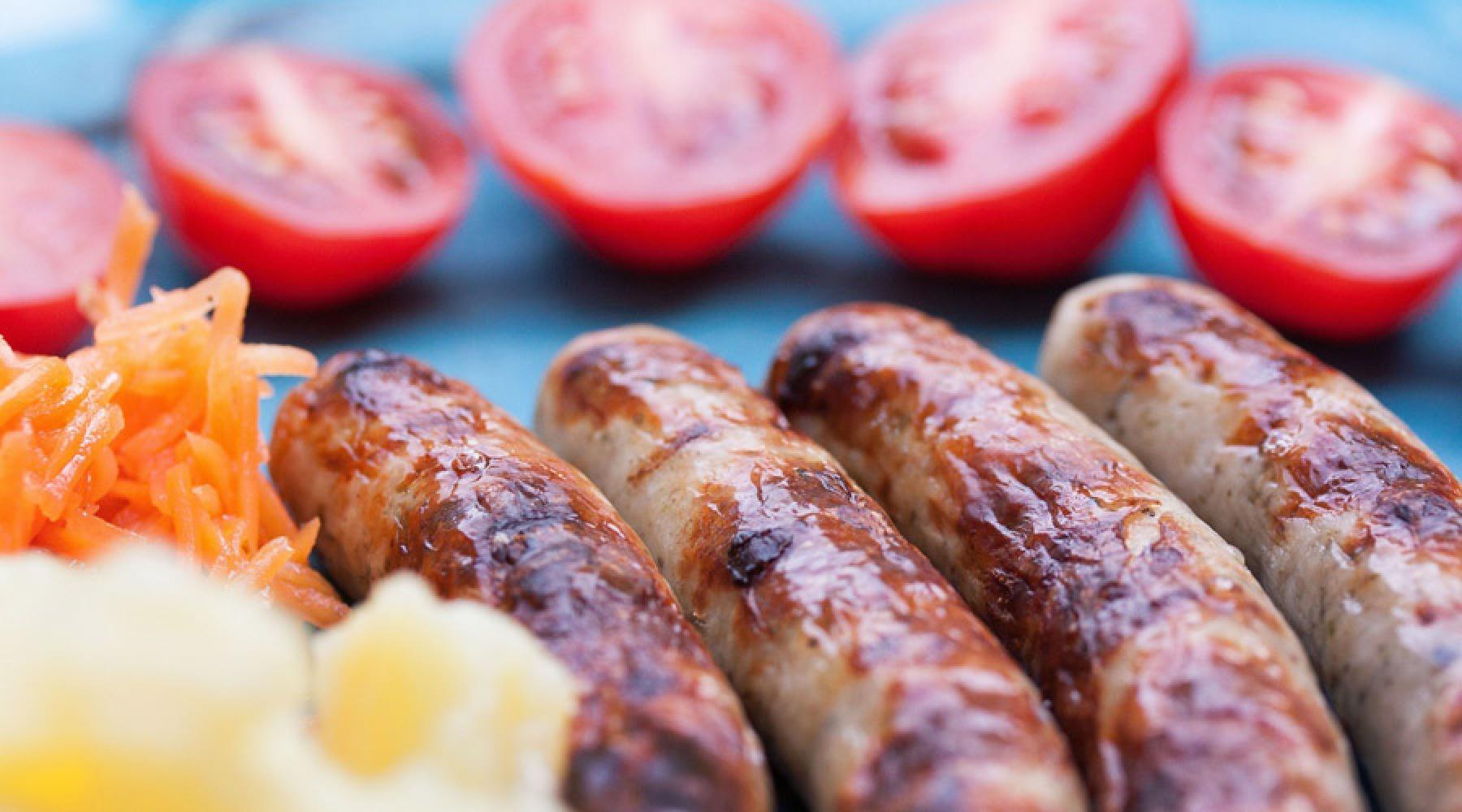 Bratwurst på en tallrik tillsammans med tomater och morotssallad