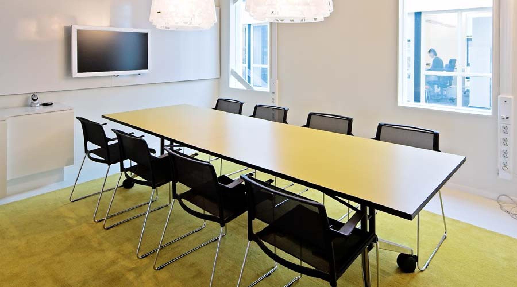 Åtta stolar står runt ett avlångt gult bord i ett av Tysk-Svenska Handelskammarens konferensrum.