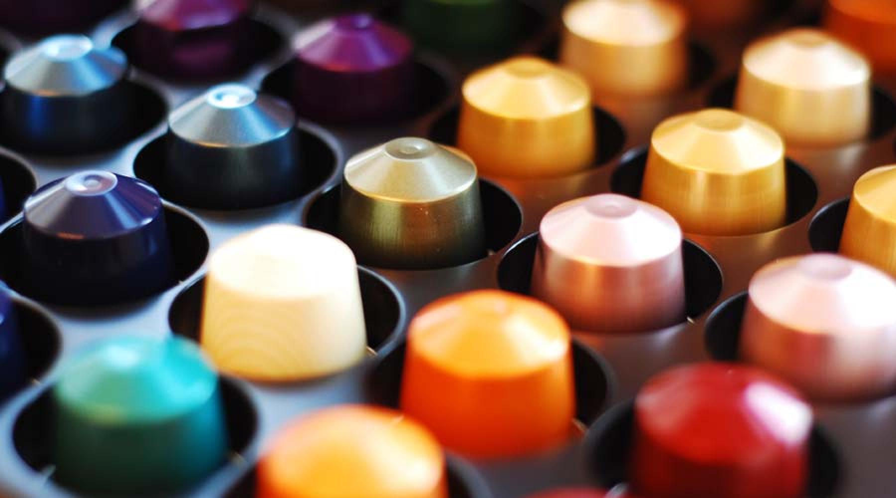 Flera Nespresso-kaffekapslar i olika färger i en plastbehållare