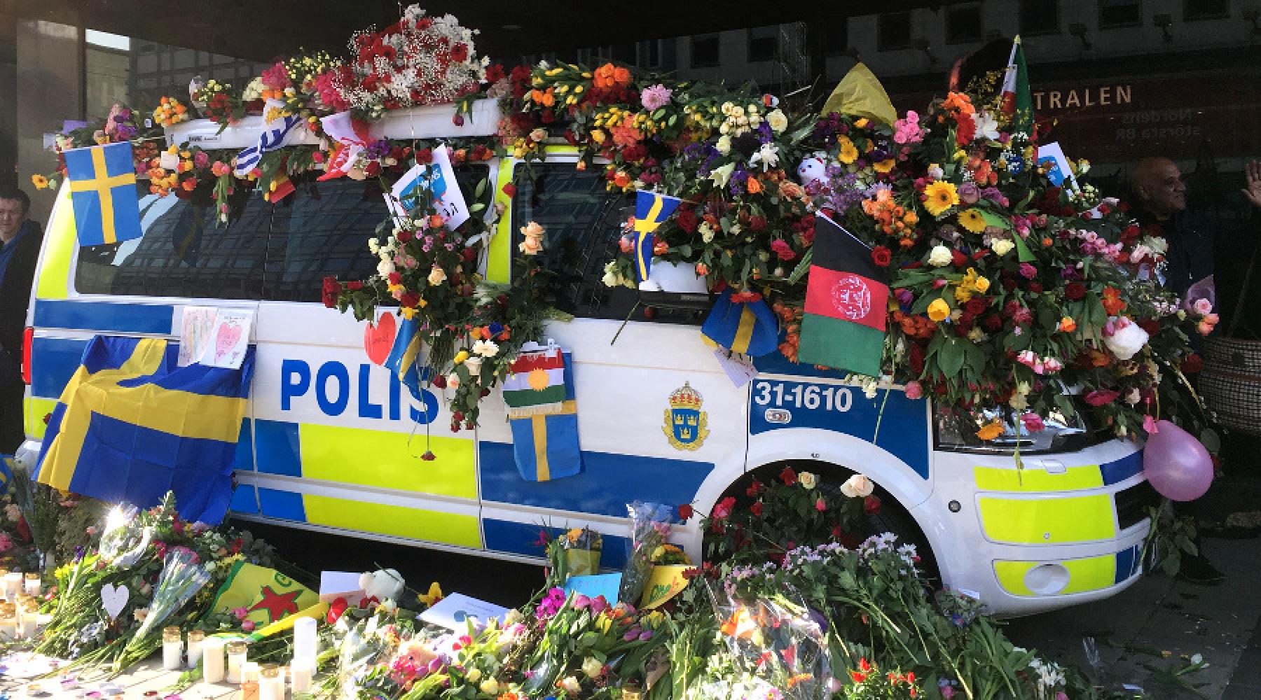 Ein schwedisches Polizeiauto in der Stockholmer Innenstadt ist überfüllt mit Blumen, Fahnen und Dankesbotschaften