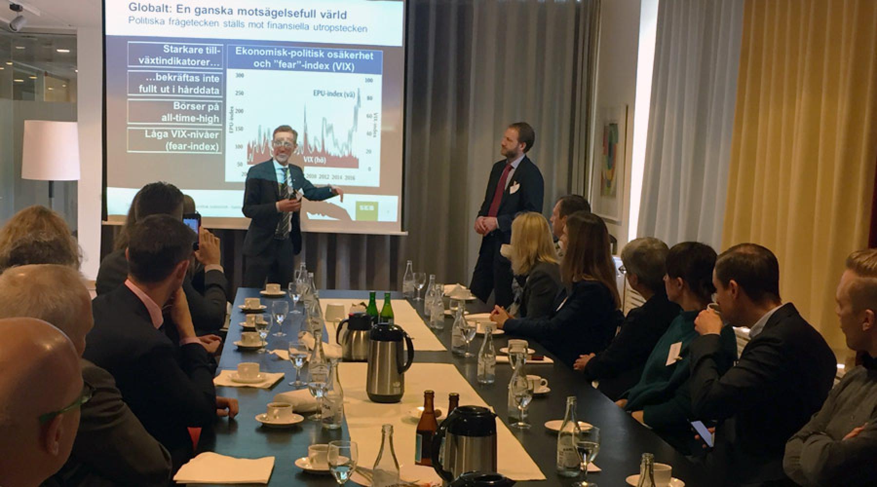Robert Bergqvist står framför en datorprojektion. Seminariedeltagarna sitter uppradade på ett långt bord.