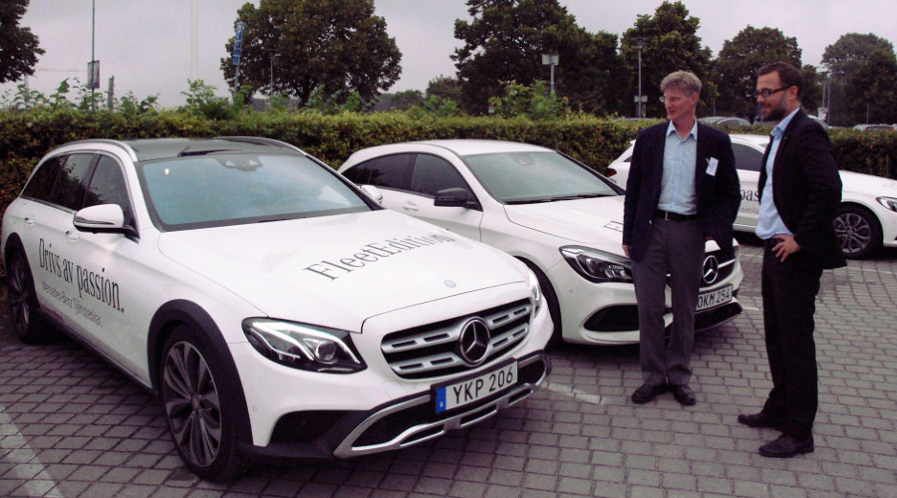 Zwei Männer stehen neben mehreren weißen Mercedes auf dem Parkplatz vor der Villa Källhagen.