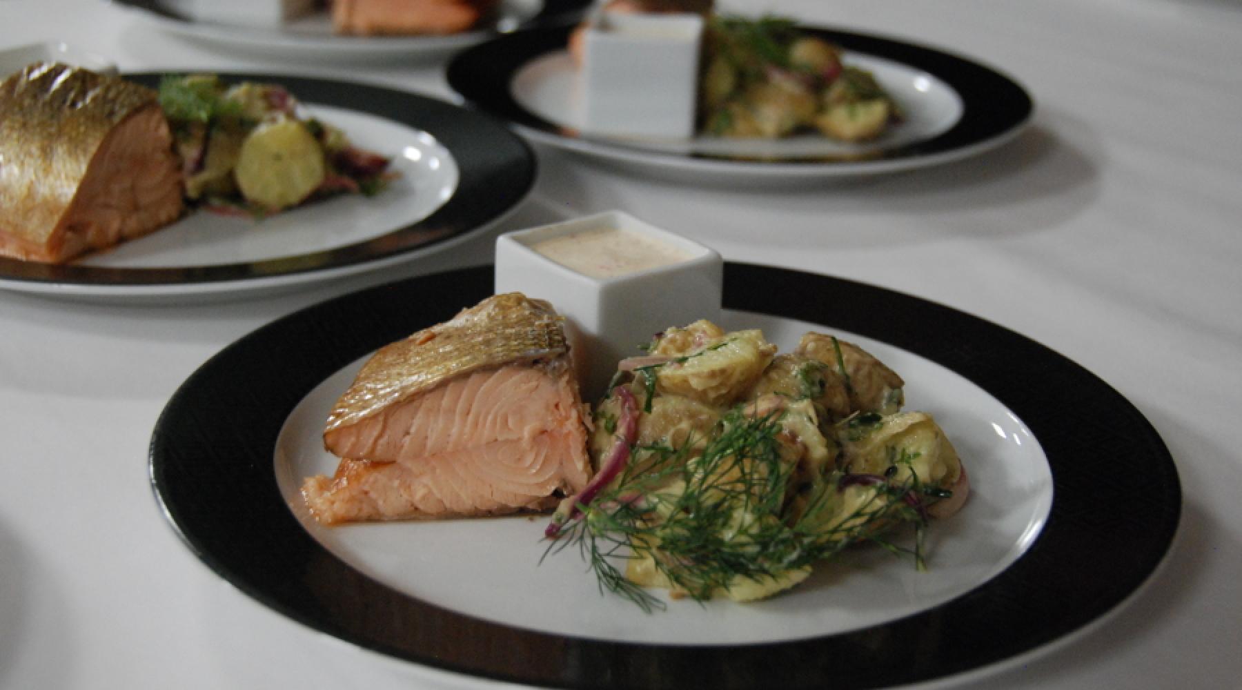 En lunchtallrik med varmrökt lax, potatissallad och sås