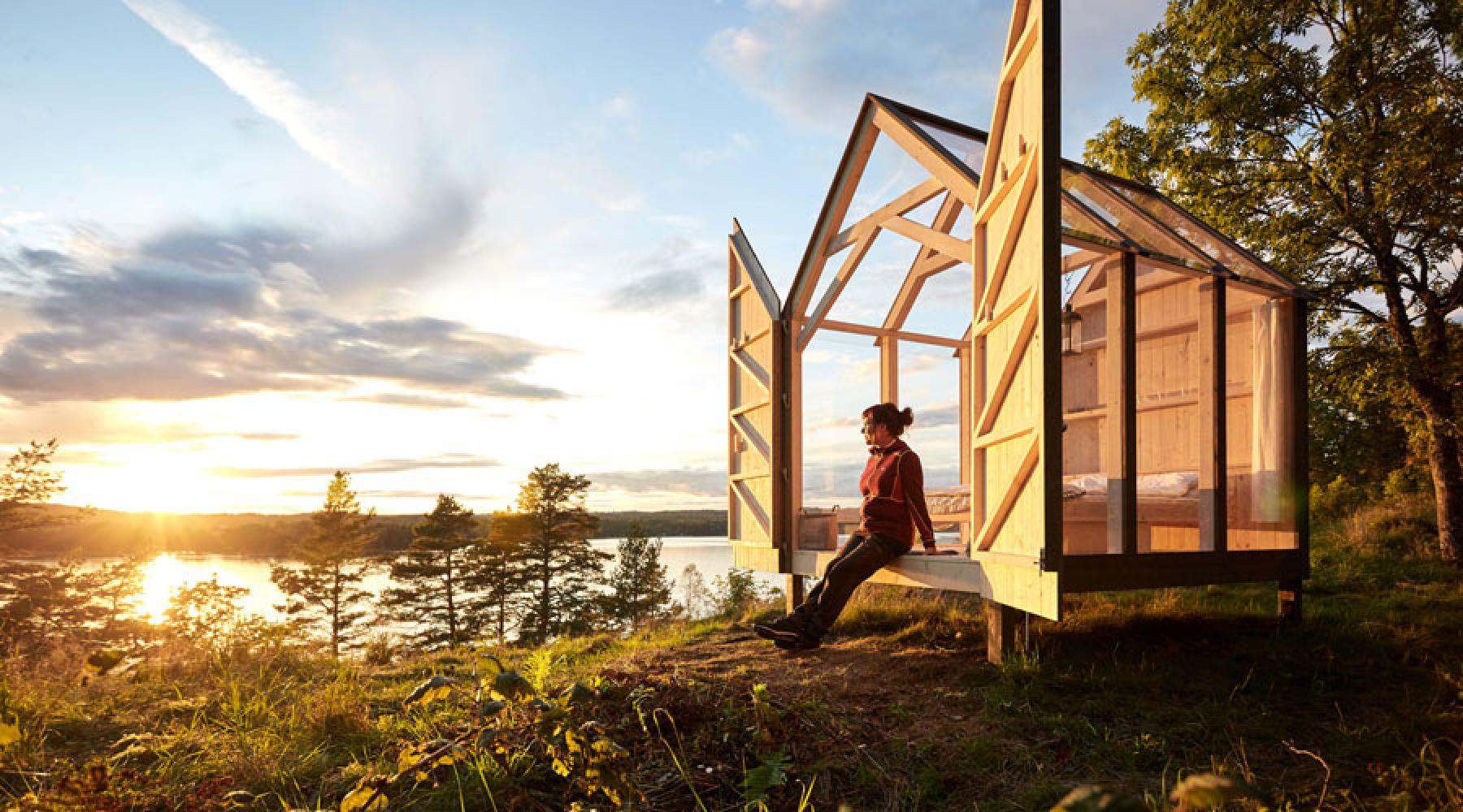 Eine Frau sitzt in einer der Glaskabinen, die Visit Sweden für die Initiative The 72 Hour Cabin errichten ließ.