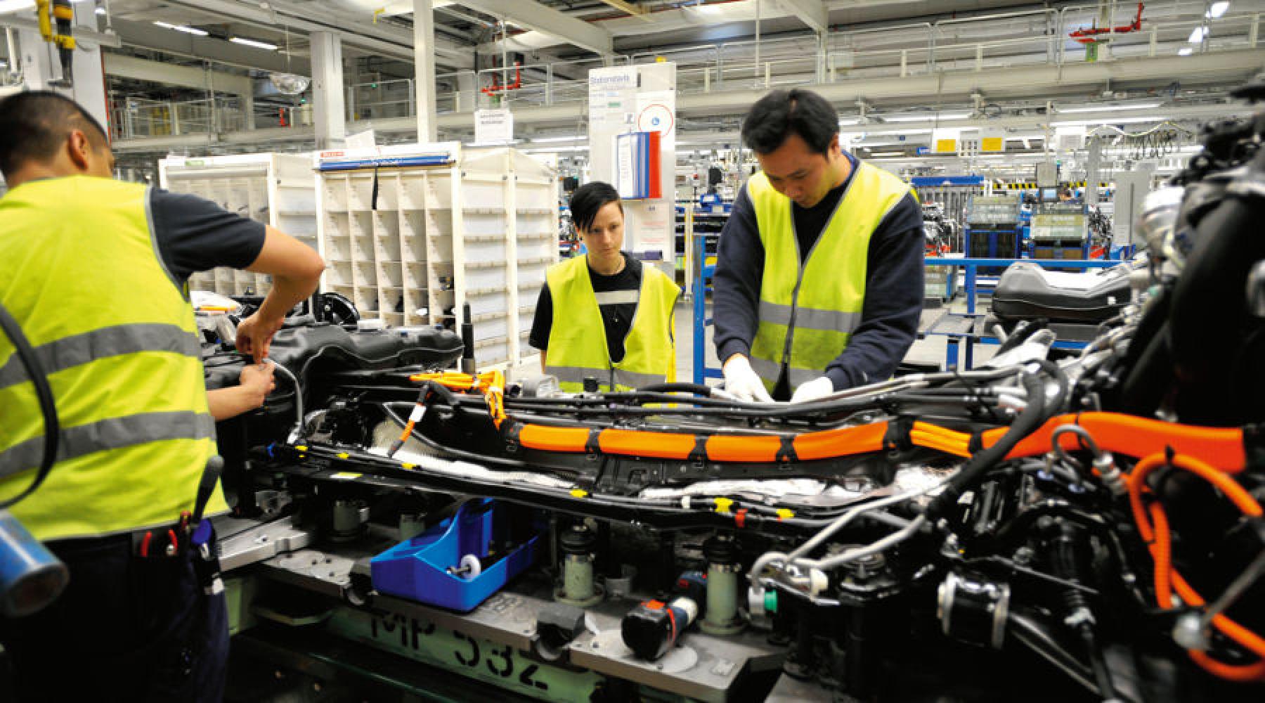 Mehrere Personen arbeiten in einer Fabrikshalle.