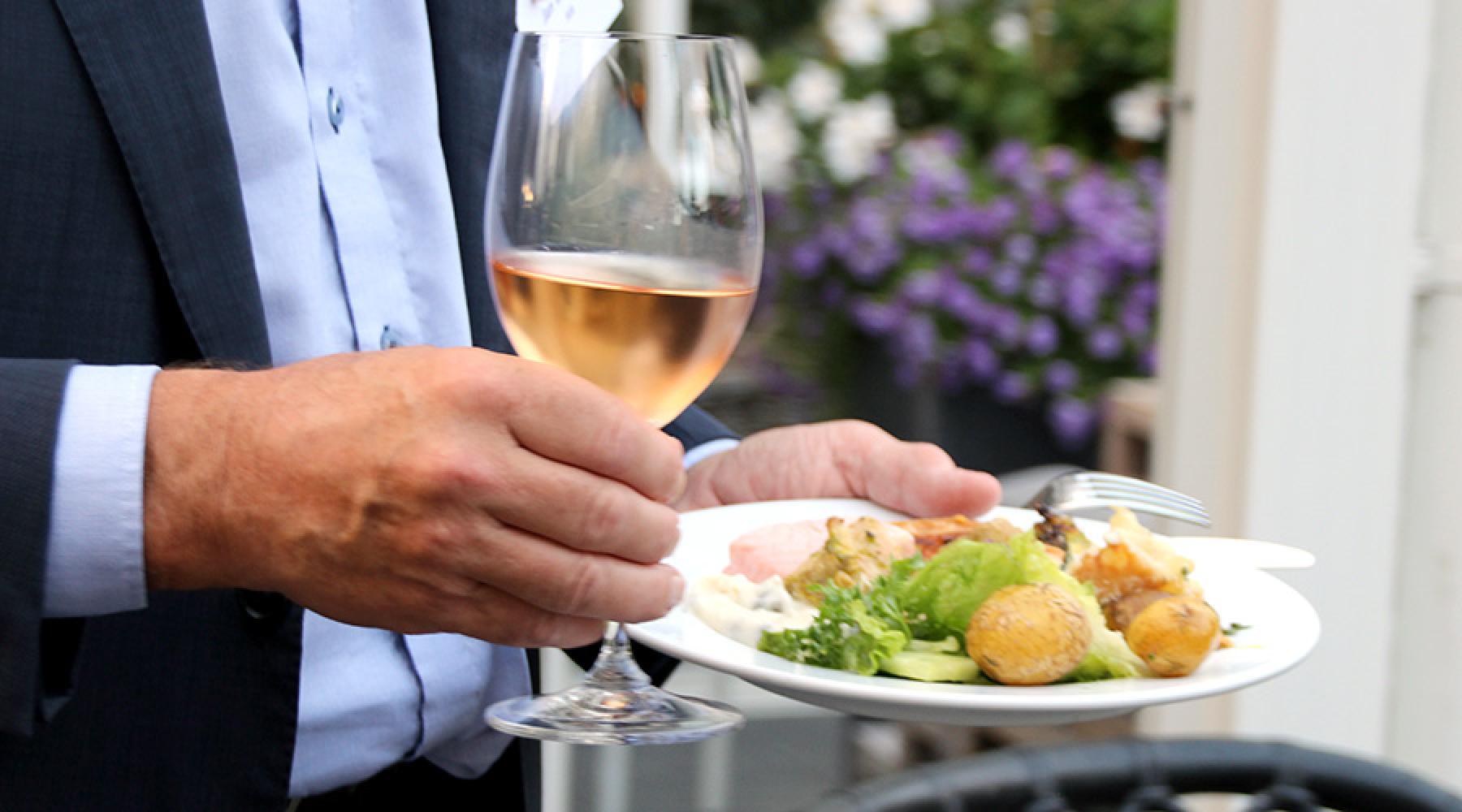 En person med en mattallrik och ett glas vin på Tysk-Svenska Handelskammarens business kickoff 2018