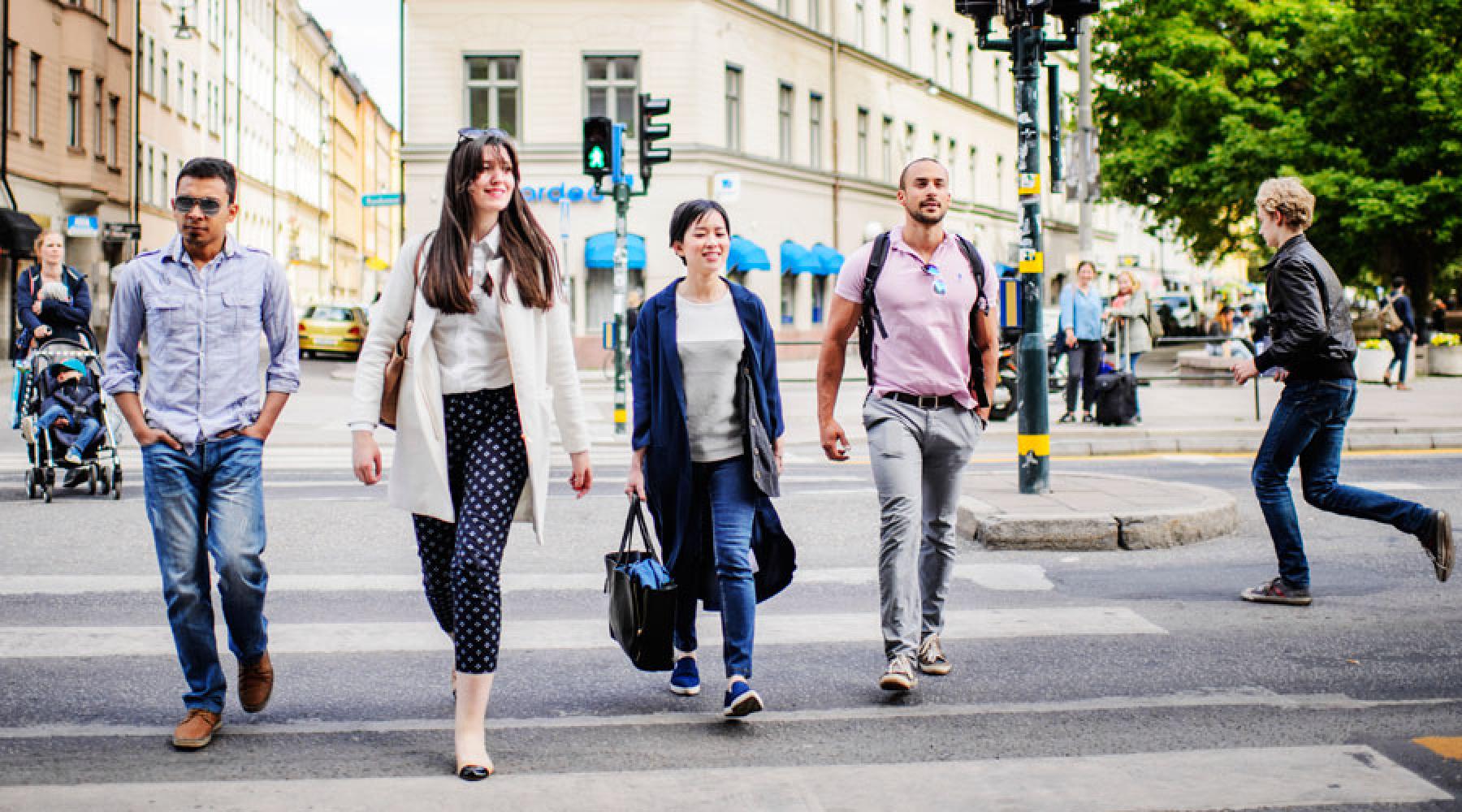 Sechs Personen überqueren eine Straße in Stockholm an einer Fußgängerampel