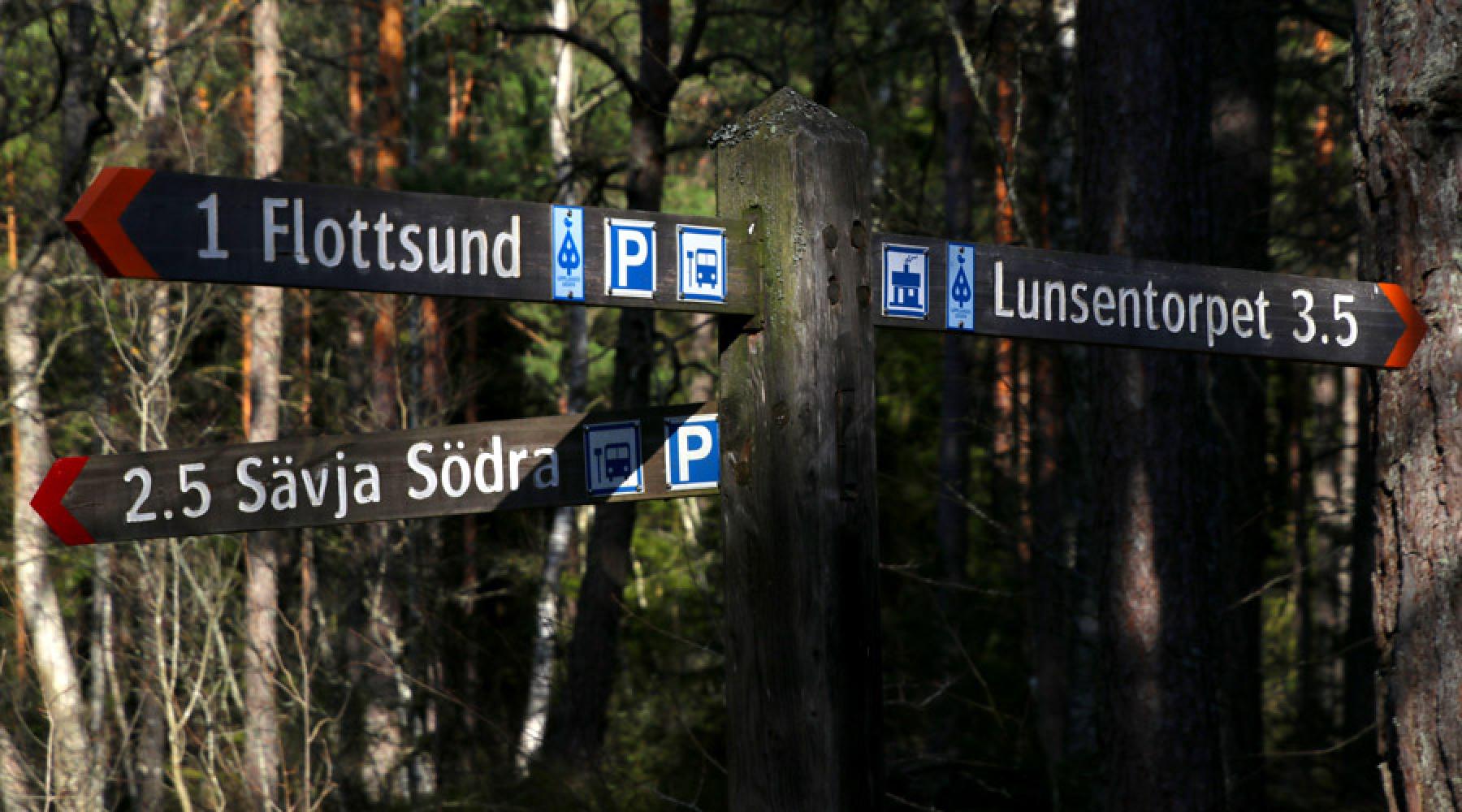 Ein Wegweiser mit drei Schildern in einem Wald nahe Uppsala