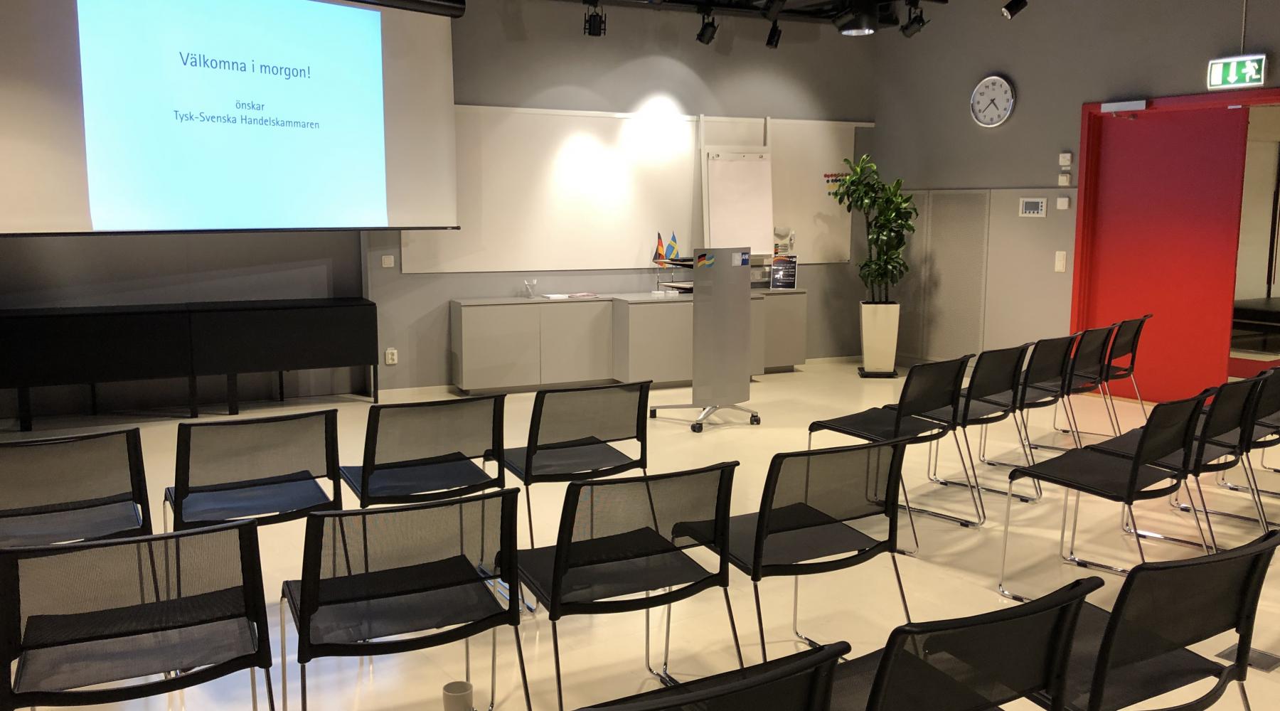 Stolar i biosittning samt projektorduk och whiteboard i Tysk-Svenska Handelskammarens seminarierum i Stockholm.