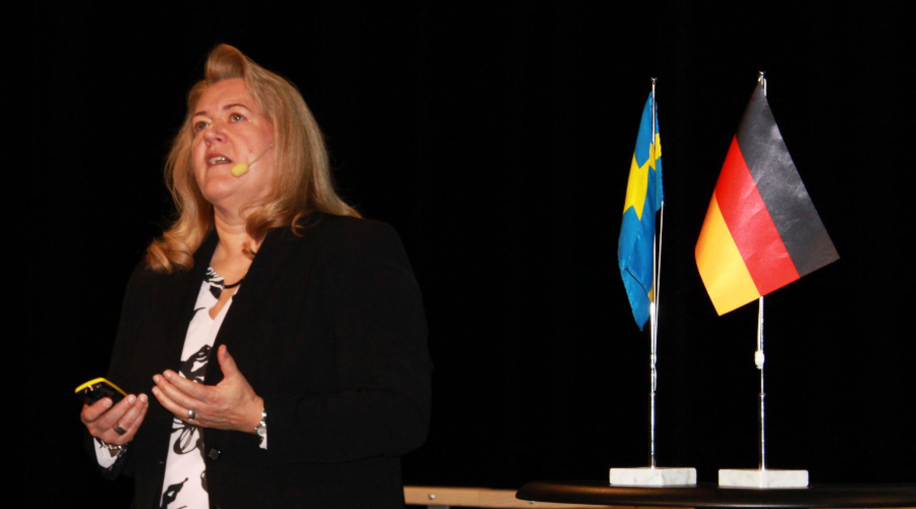 Vorstandsmitglied Andrea Fuder von Volvo Group Trucks mit einer schwedischen und deutschen Flagge bei einem Studienbesuch der Deutsch-Schwedischen Handelskammer in Göteborg