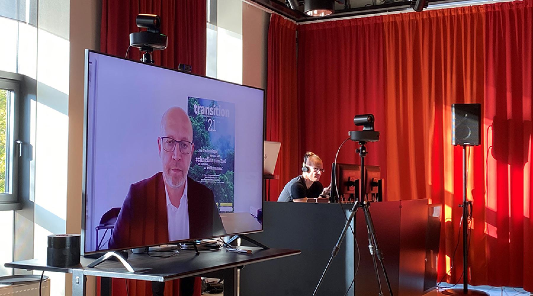 Bild av Andreas Kuhlmann, vd för tyska energiorganisationen Deutsche Energiagentur (Dena) som deltar digitalt på en stor skärm i Tysk-Svenska Handelskammarens studio.