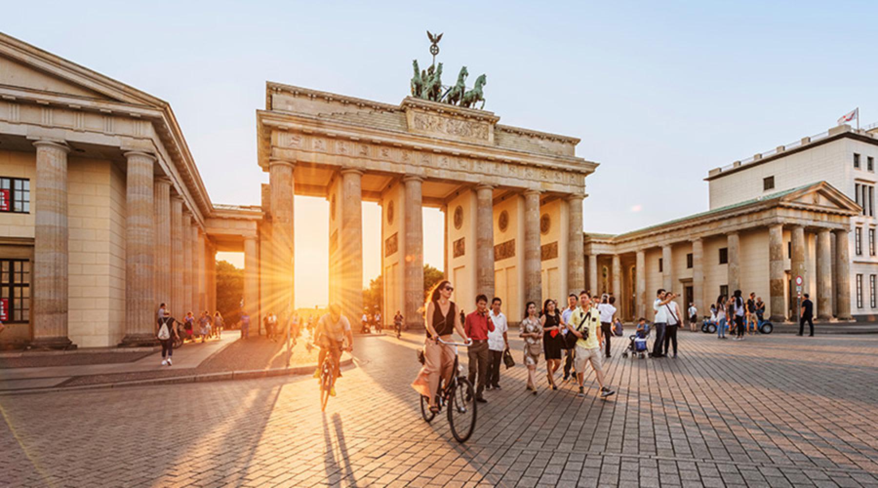 Cyklande och promenerande människor framför Brandenburger Tor i Berlin