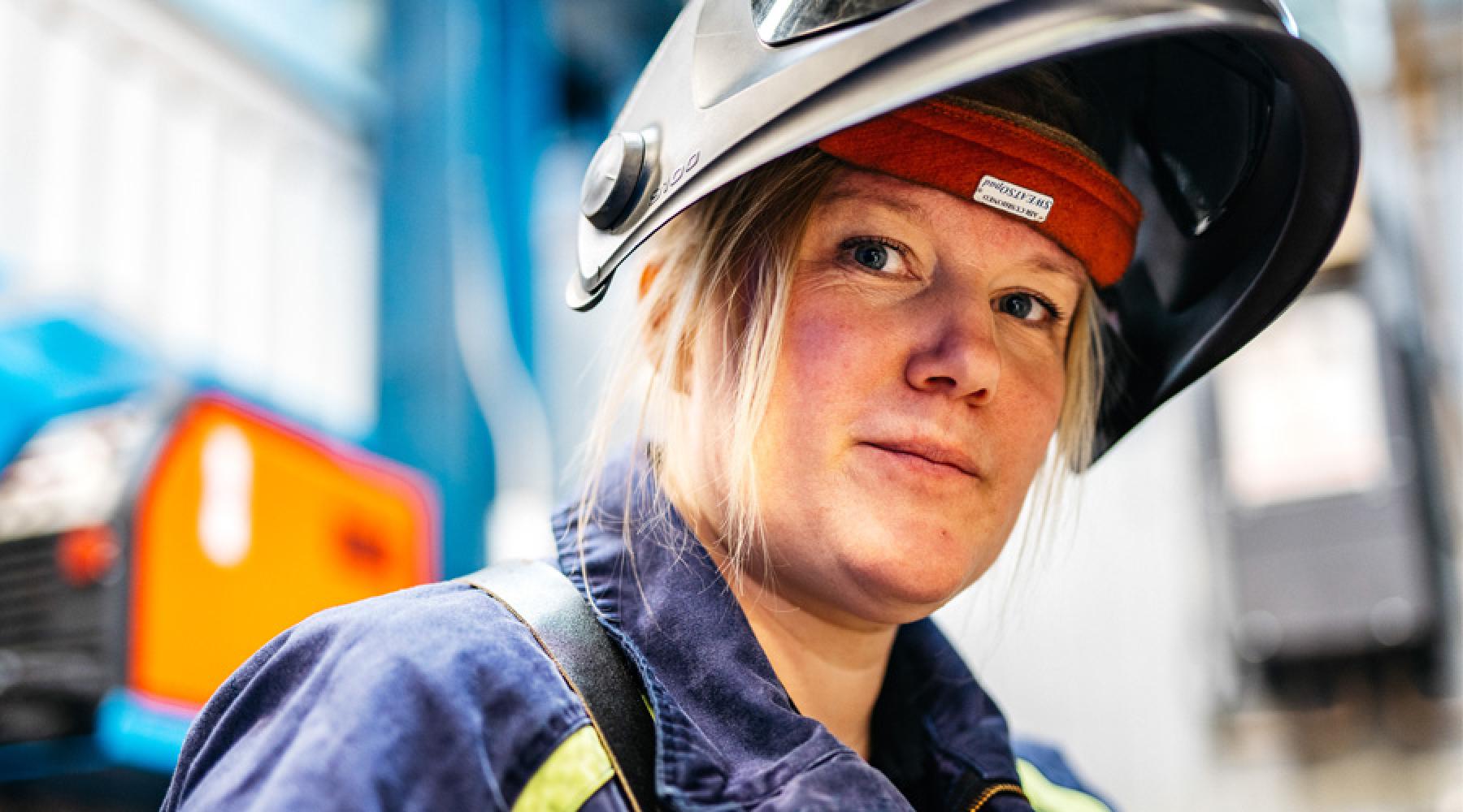 Kvinna med svetshjälm i verkstad